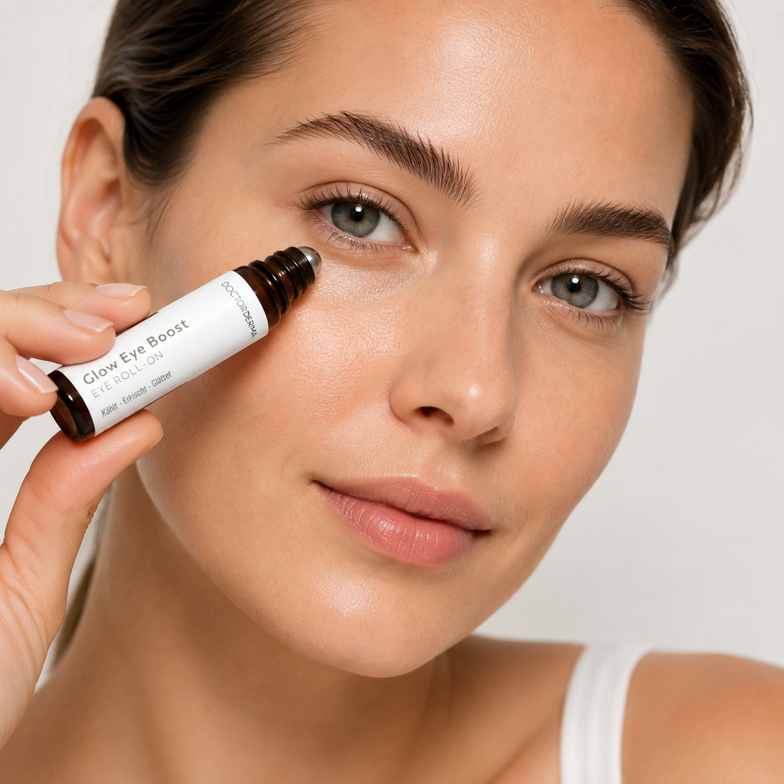 Frau trägt DOCTOR DERMA Glow Eye Boost Roll-on unter der Augenpartie auf